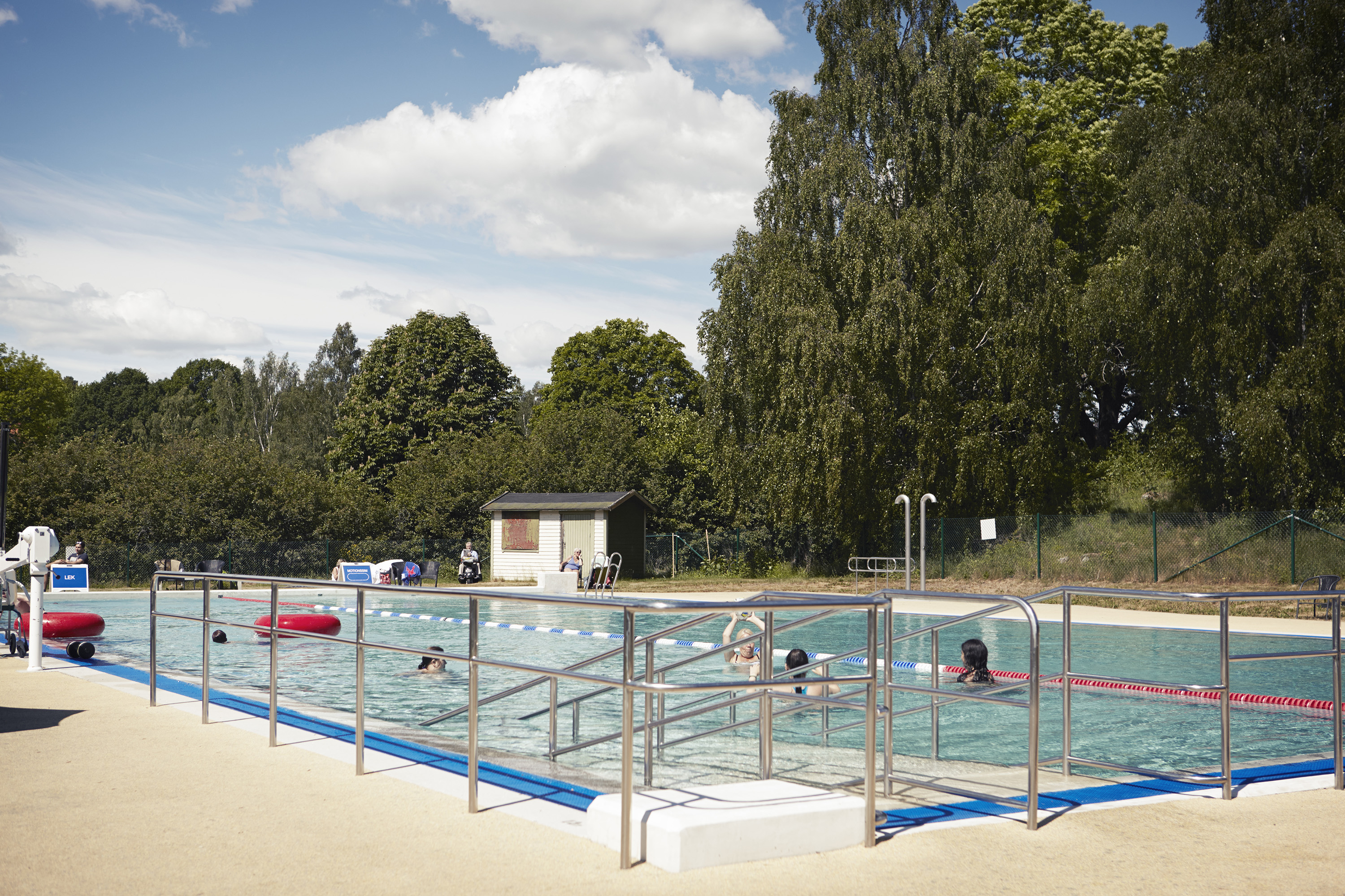 Utomhusbassäng, omgiven av lummiga träd.