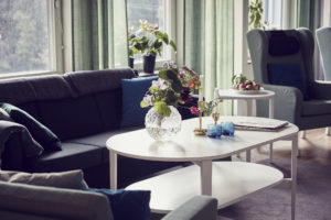 En trevlig soffhörna, med blommor i fönster och på soffbordet.