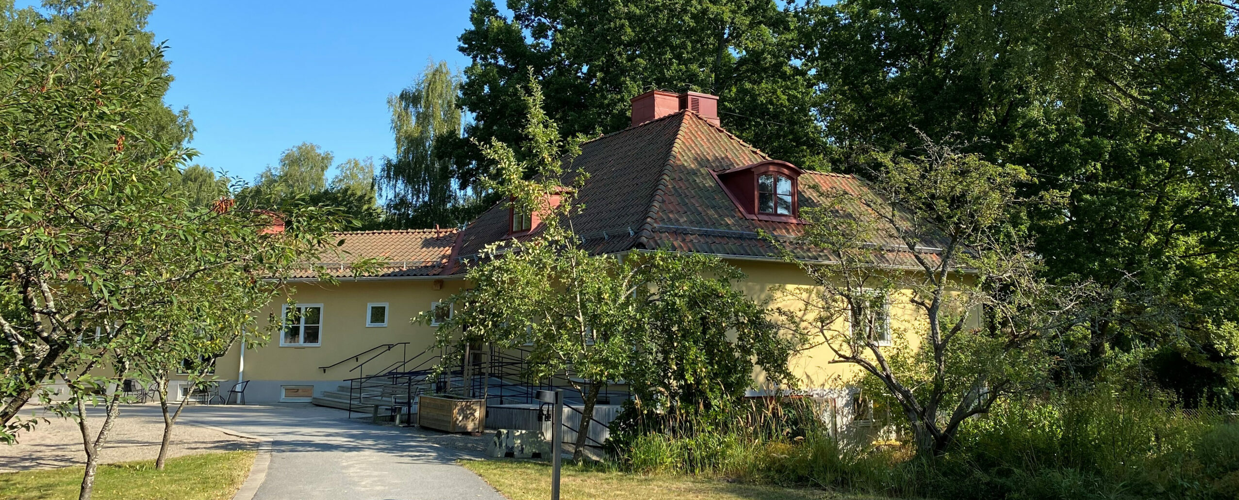 Diakonala enhetens gula villa i lummig trädgård.