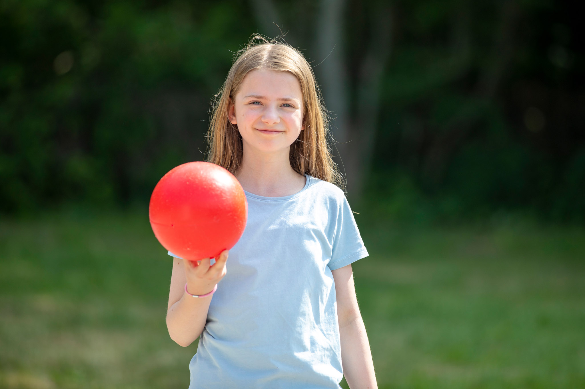 Leende tjej som håller i röd boll.