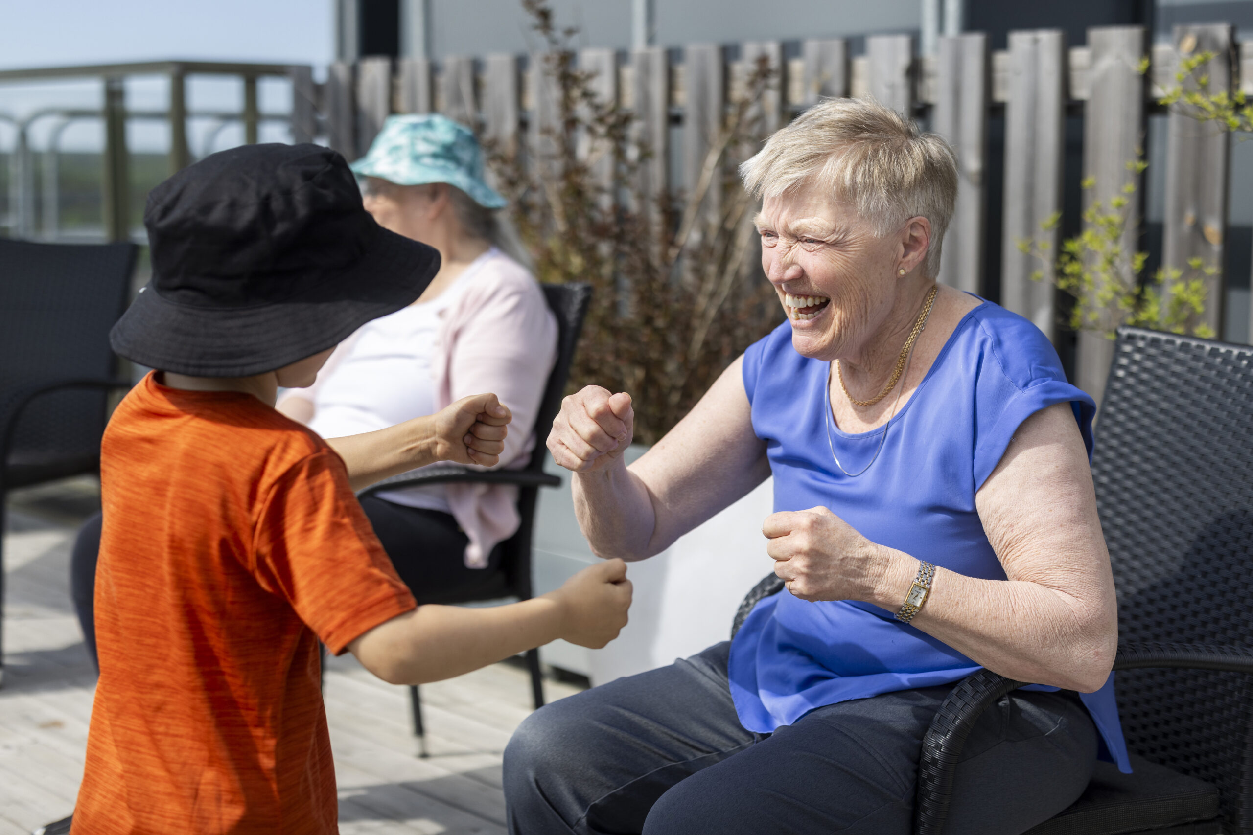 Barn och äldre kvinna boxas på lek utomhus.