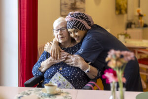 Medarbetare omfamnar en äldre kvinna.