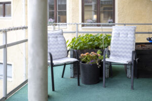 Sittplatser på balkong, vid krukor med blommor.