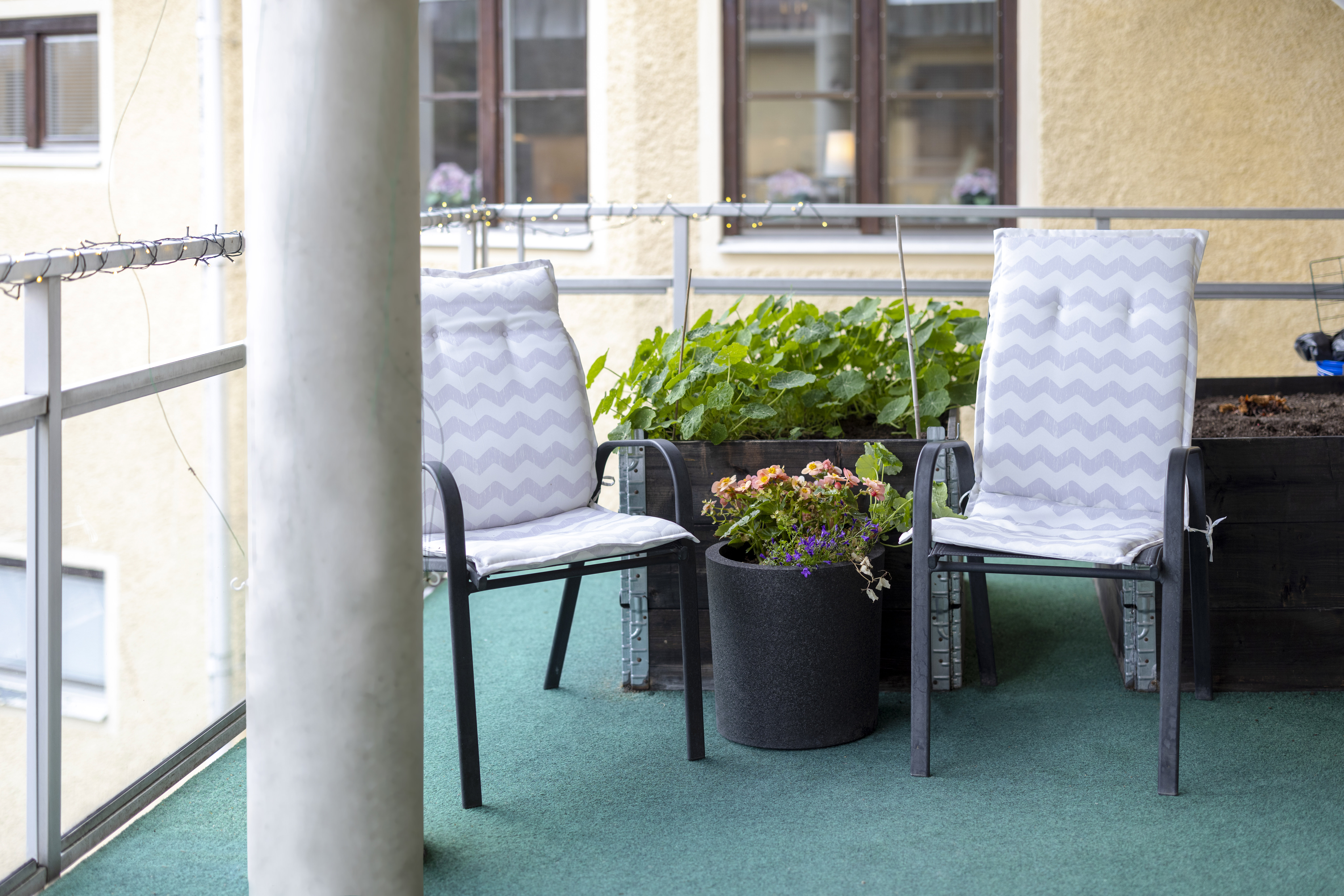 Sittplatser på balkong, vid krukor med blommor.