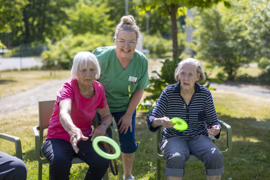 Två boende kastar ringar i spel, påhejad av personal.